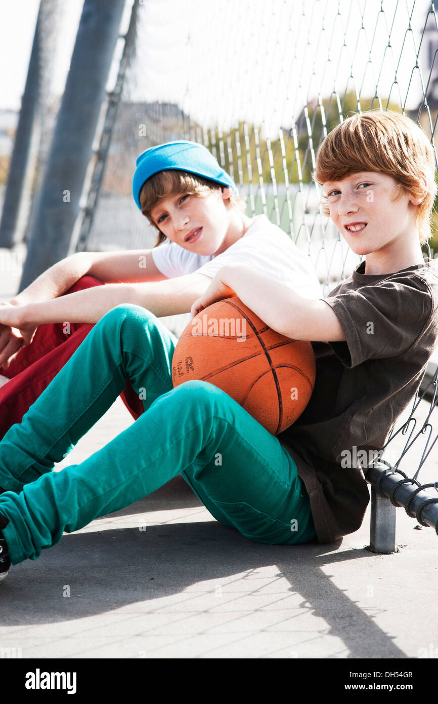 Cool deux garçons assis avec un terrain de basket-ball sur un terrain de jeu Banque D'Images