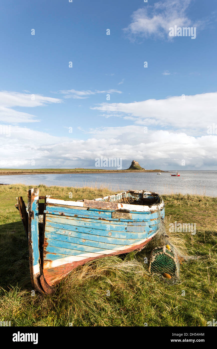 Coble en bois de bateaux de pêche sur l'Île Sainte et le lointain Château de Lindisfarne, Northumberland, England, UK Banque D'Images