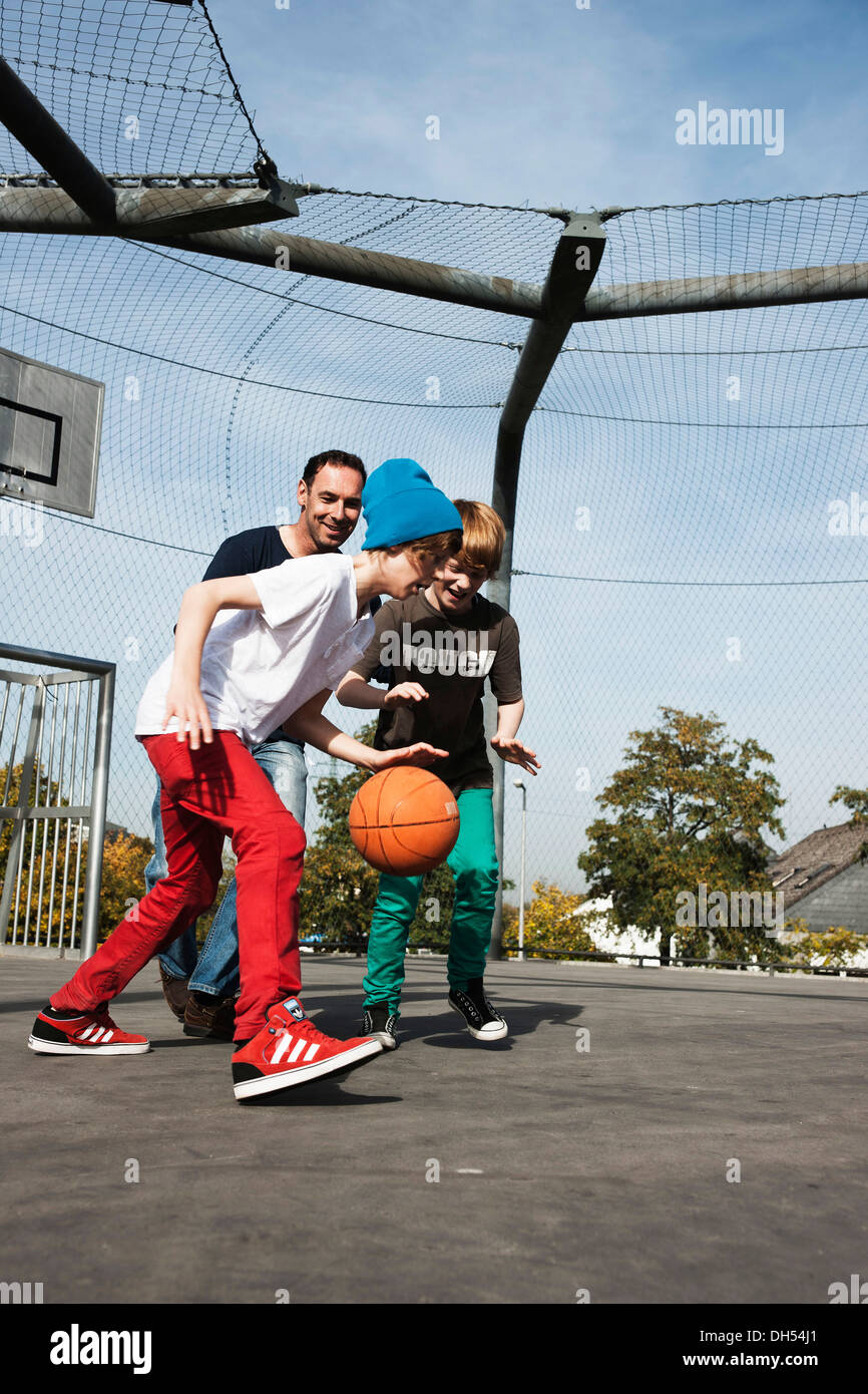 Cool deux garçons jouant au basket-ball avec leur père Banque D'Images