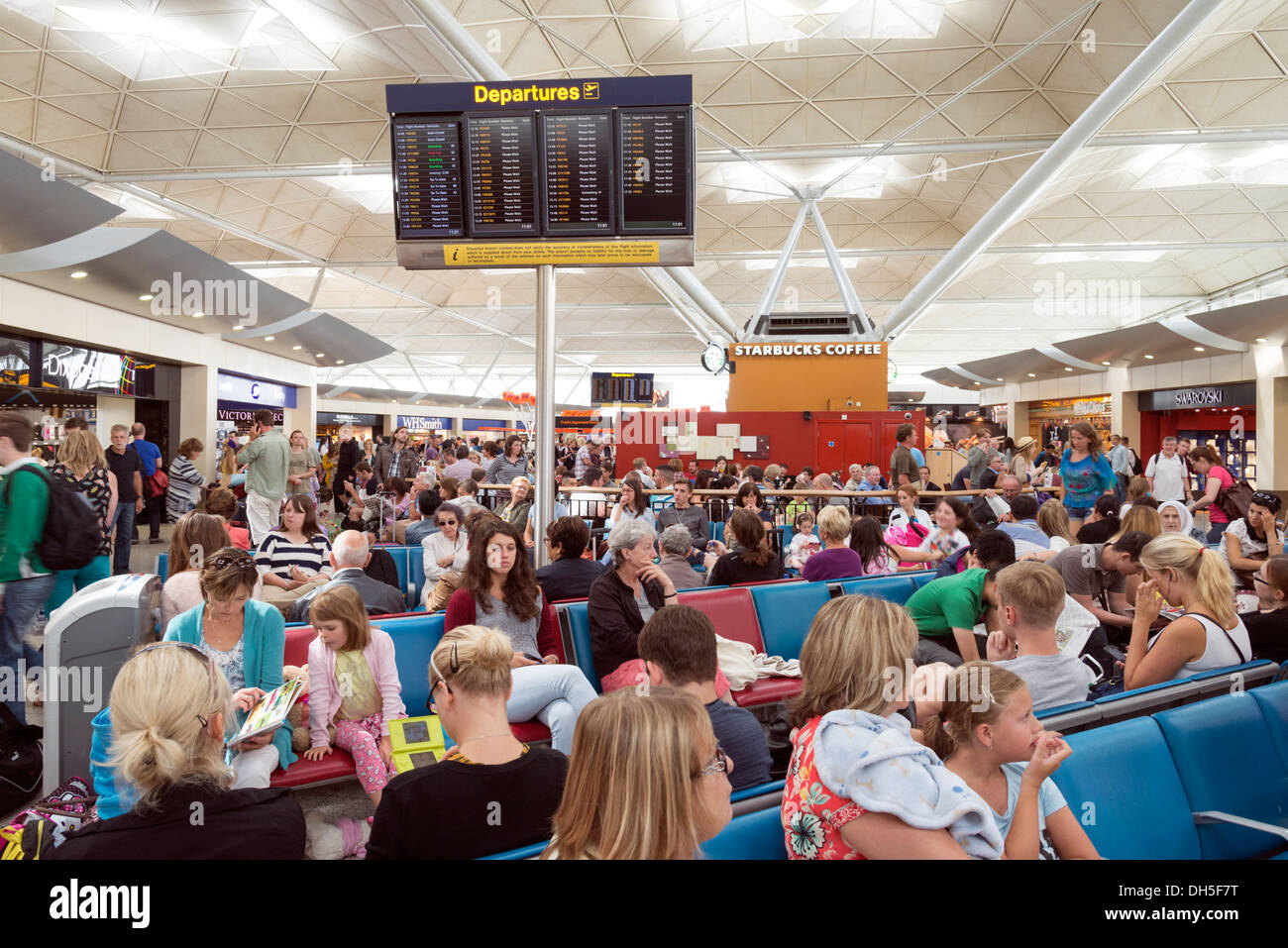 Les gens qui attendent dans le salon des départs de l'aéroport de Stansted, Angleterre, RU Banque D'Images