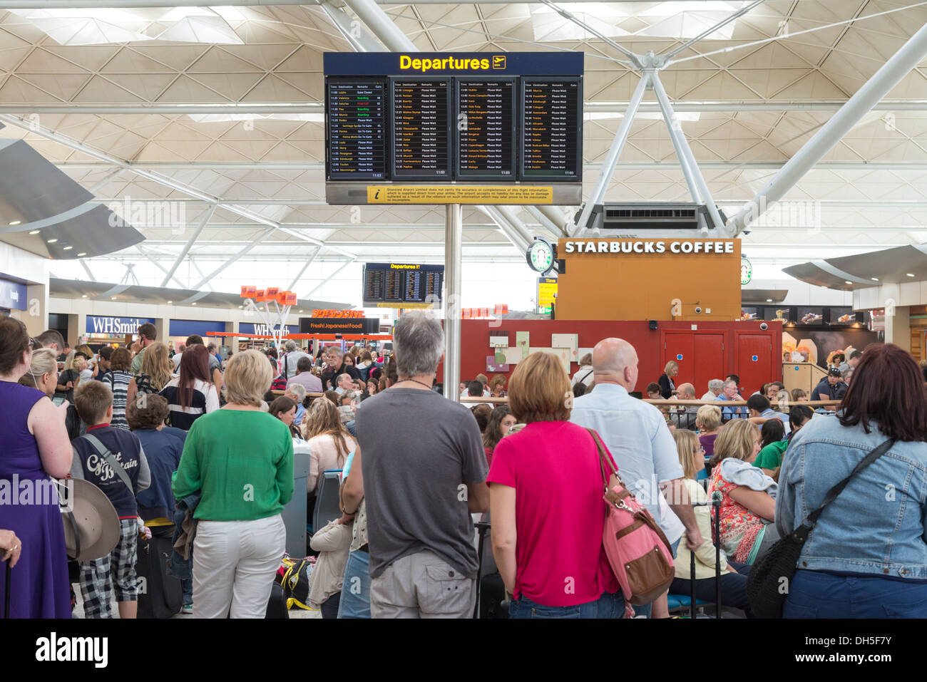 Les gens qui attendent dans le salon des départs de l'aéroport de Stansted, Angleterre, RU Banque D'Images