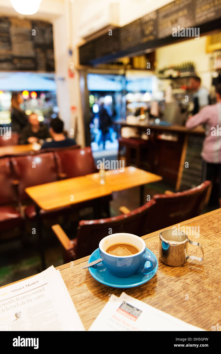 Lire le journal et le temps tout en buvant un café dans un café de Melbourne. Banque D'Images