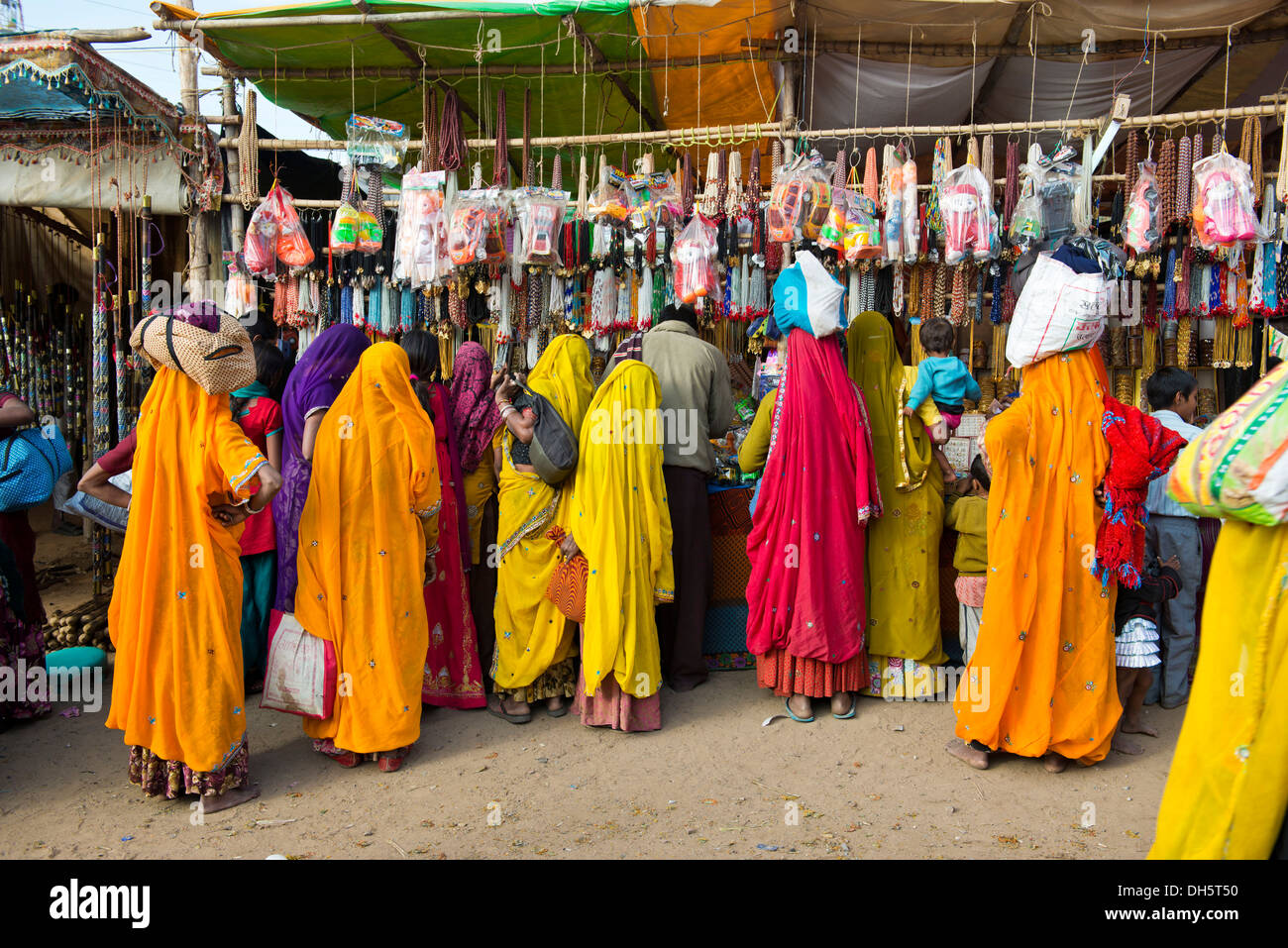 Les femmes indiennes en saris colorés, debout devant un étal vendant des jouets et des bijoux de mode, Pushkar, Pushkar Fair Camel Banque D'Images