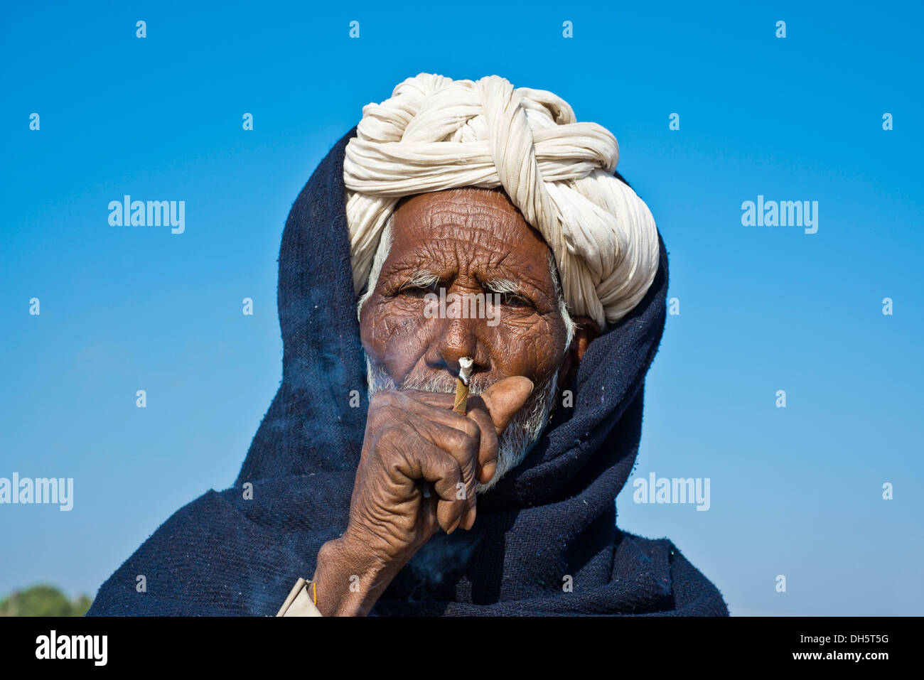 L'homme indien avec un turban blanc fumer une cigarette bidi, Pushkar, Rajasthan, India Banque D'Images