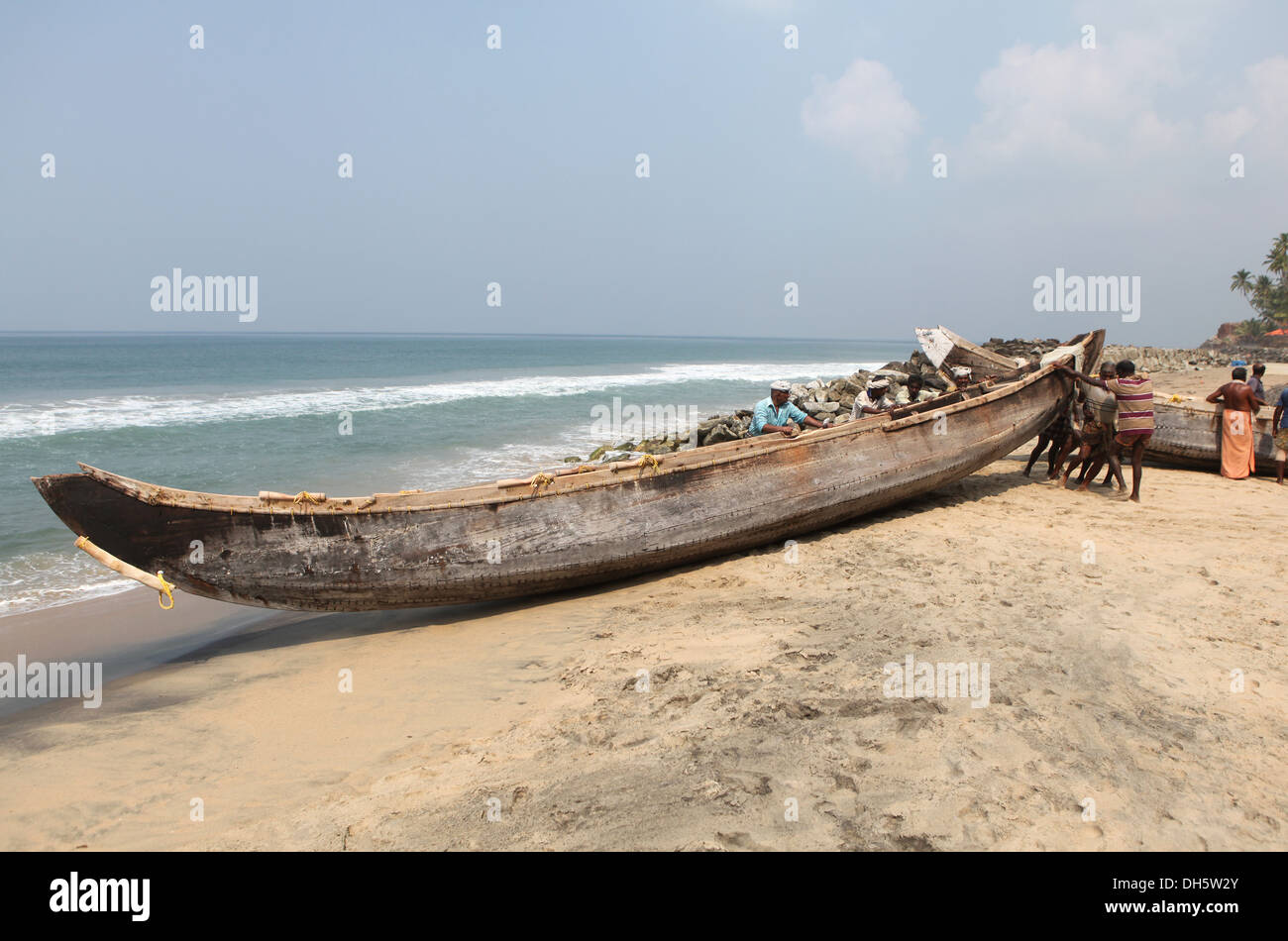 Les pêcheurs poussant leur bateau de l'eau sur la plage, Varkala, Kerala, Inde, Asie Banque D'Images