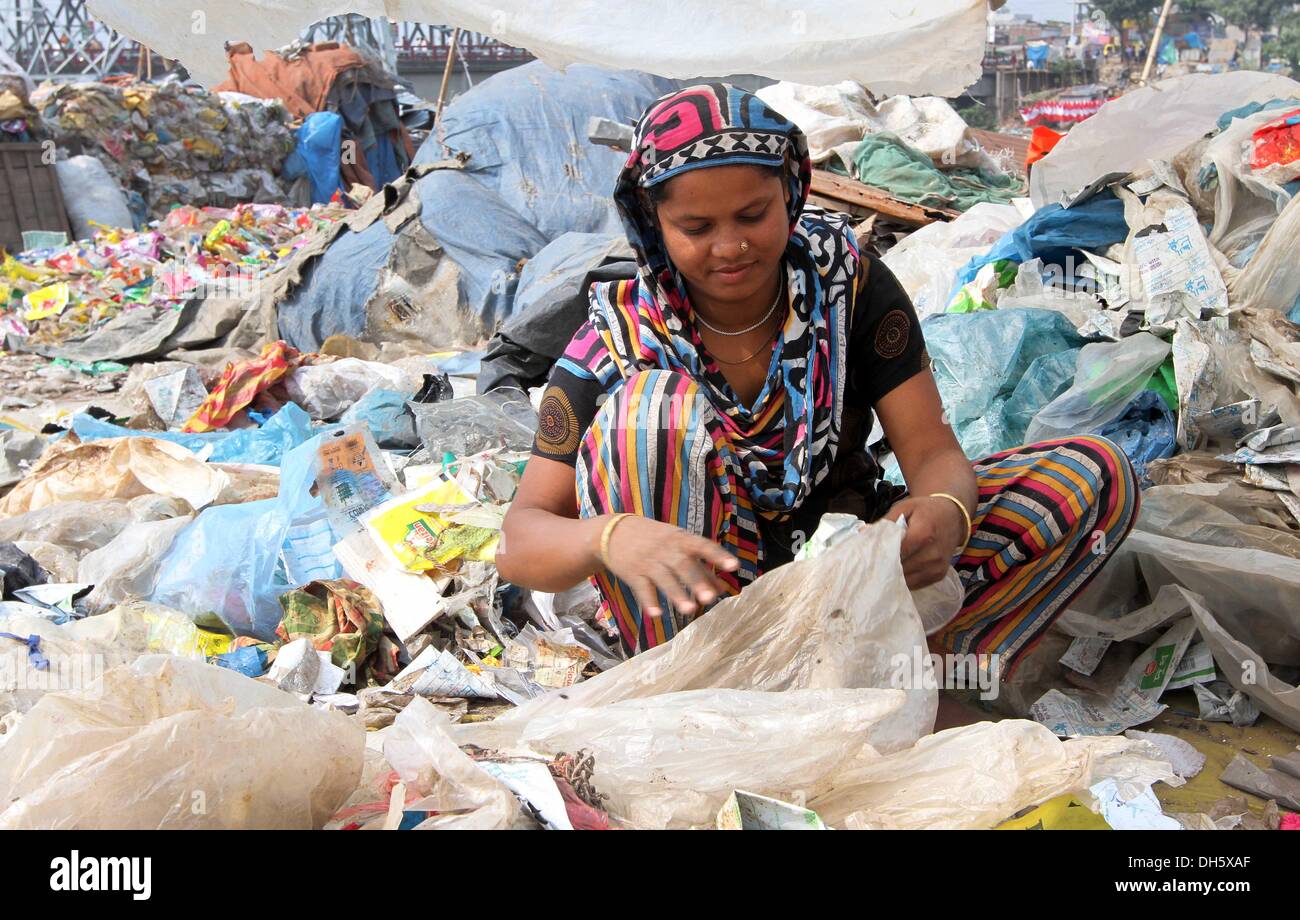 01 novembre 2013. Les femmes du Bangladesh par l'entremise de récupération en plastique polyéthylène utilisé dans une usine de recyclage à Dhaka. Les travailleurs de recyclage au Bangladesh, un des pays les plus pauvres du monde, rendre le recyclage du plastique dans les conditions de travail et les primitives sont payés 2 dollars par jour. Même les enfants qui travaillent dans ces conditions de travail et risquent leur vie. Tous les jours une énorme quantité de déchets de plastique sont recueillies à partir d'enfouissement et triés selon la couleur dans les usines. Plus tard, les déchets plastiques sont coupés en petits morceaux et puis fondu dans un four pour faire de divers produits. La plupart du travail est fait manuellement mais Banque D'Images