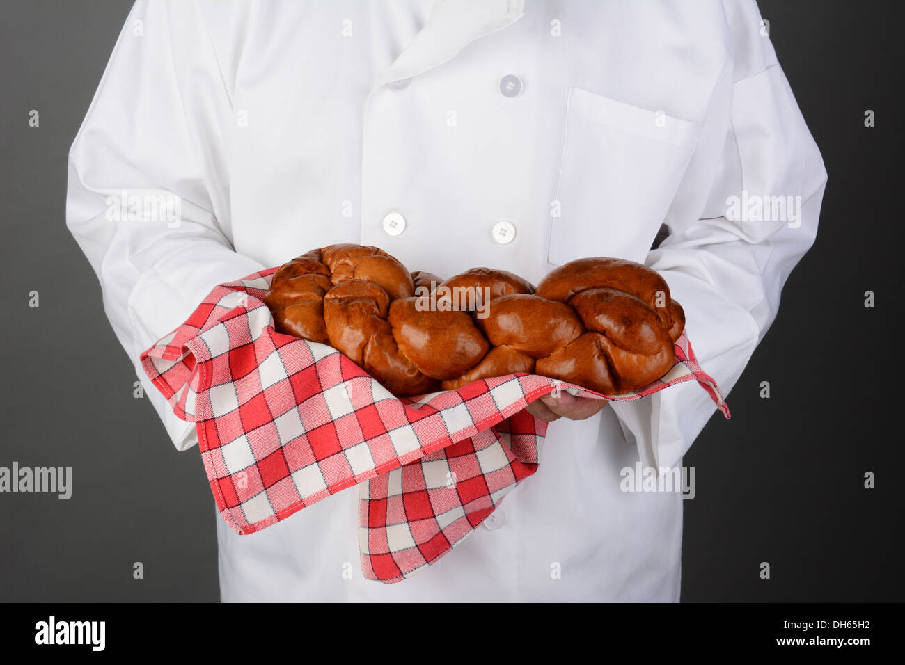 Libre d'un chef tenant une miche de pain frais cuit dans une serviette rouge à carreaux. Banque D'Images
