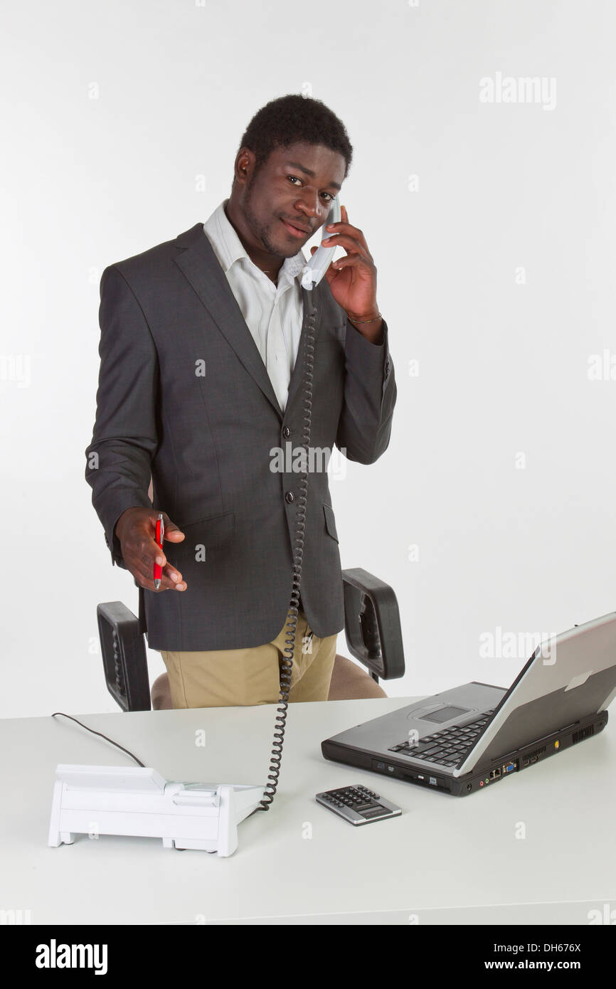 Jeune homme à la peau sombre tenant un téléphone dans un bureau Banque D'Images