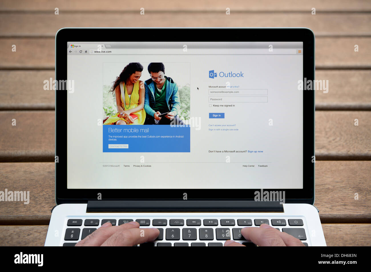 Le site Web Windows Live sur un MacBook contre un banc en bois fond de plein air y compris les doigts d'un homme (usage éditorial uniquement). Banque D'Images