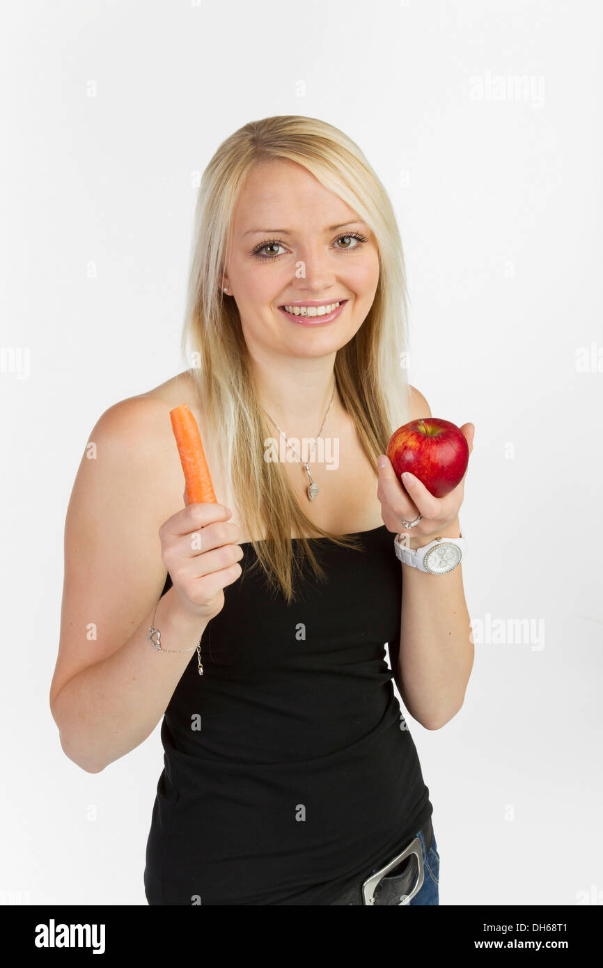 Jeune femme tenant une carotte et une pomme dans ses mains Banque D'Images
