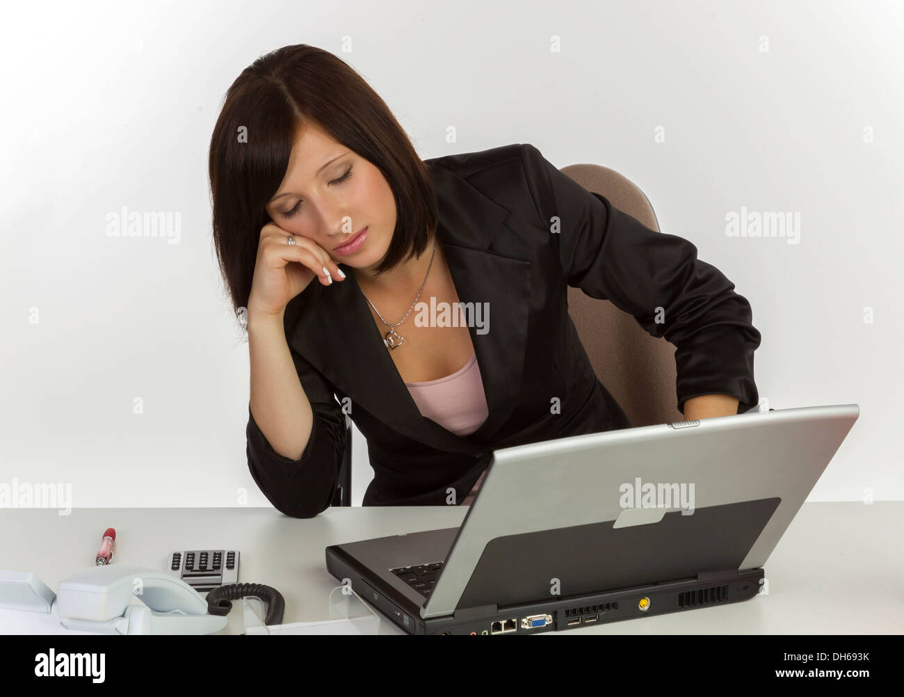 Jeune femme avec un ordinateur portable assis à un bureau et chambre Banque D'Images