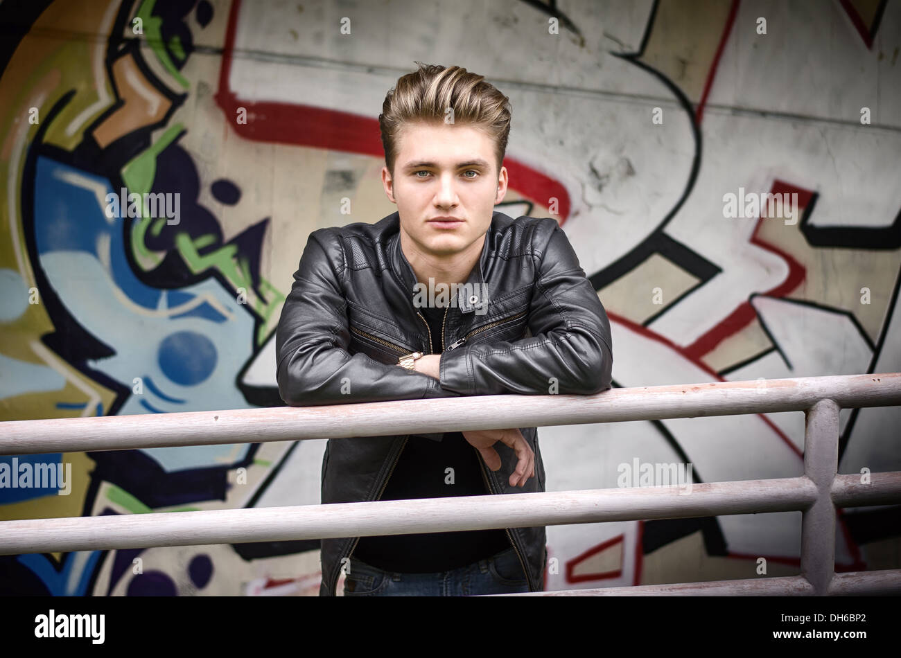 Beau jeune homme blond se penchant sur le métal forgé, dans l'environnement urbain Banque D'Images