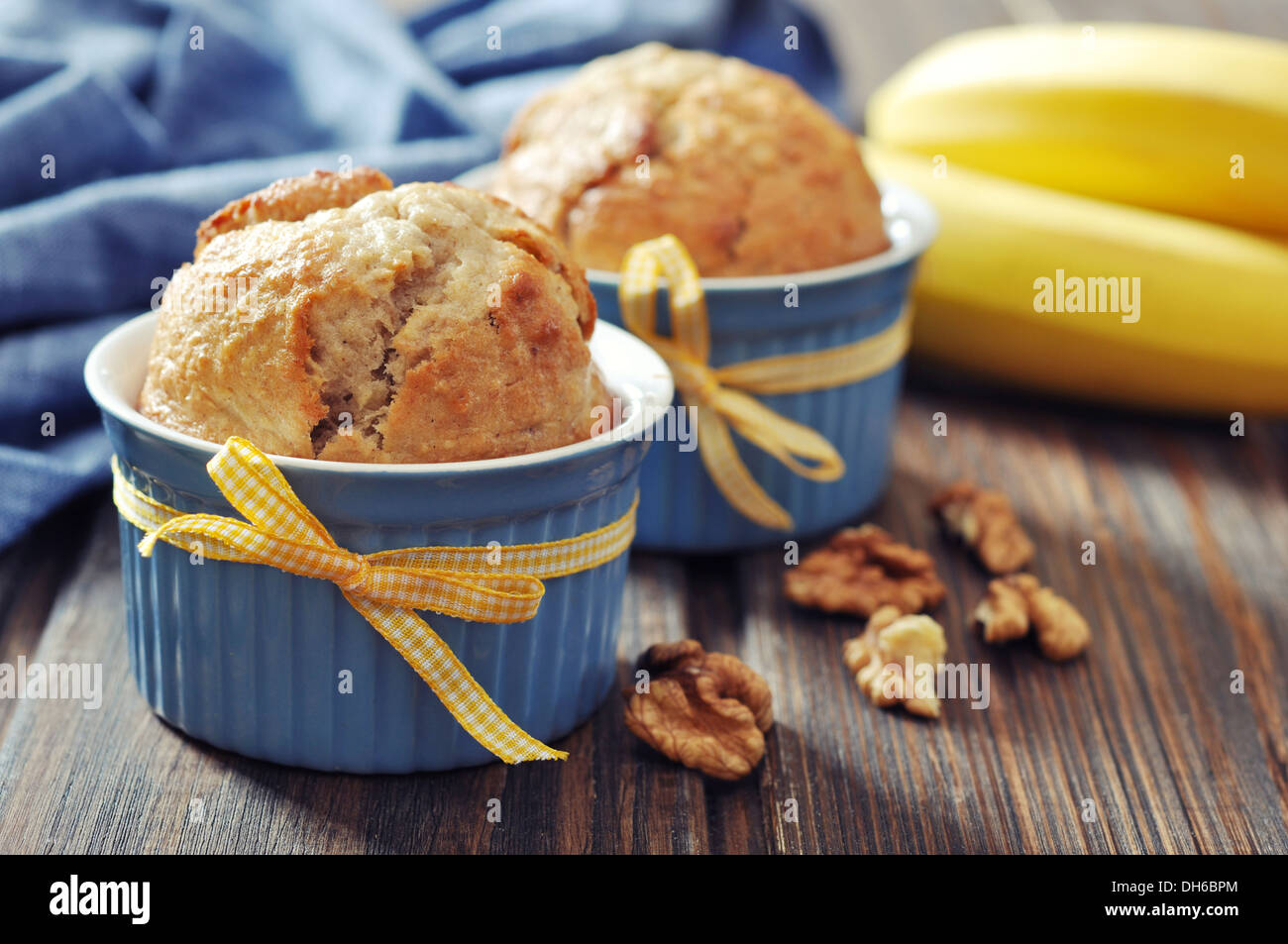 Muffins aux bananes en pâtisserie moule avec écrous sur fond de bois Banque D'Images