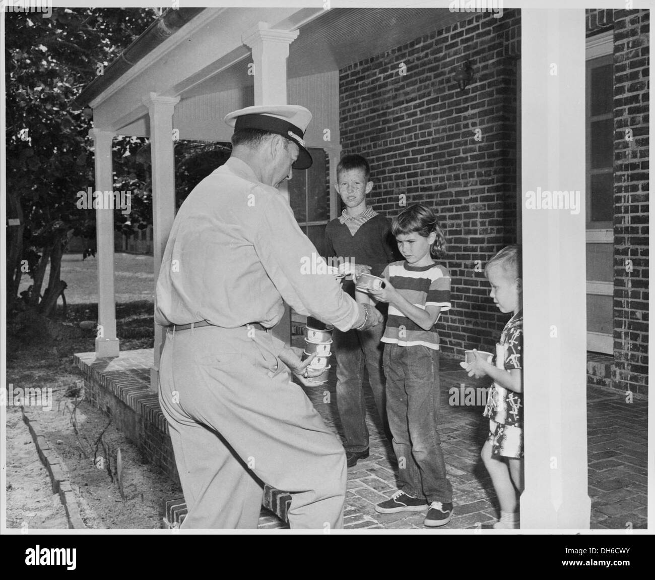 Cette image montre l'amiral Robert Dennison, l'aide navale du président, distribuant de la crème glacée aux enfants, probablement lors d'un événement public ou d'une visite officielle, mettant en valeur son implication dans les activités communautaires. Banque D'Images