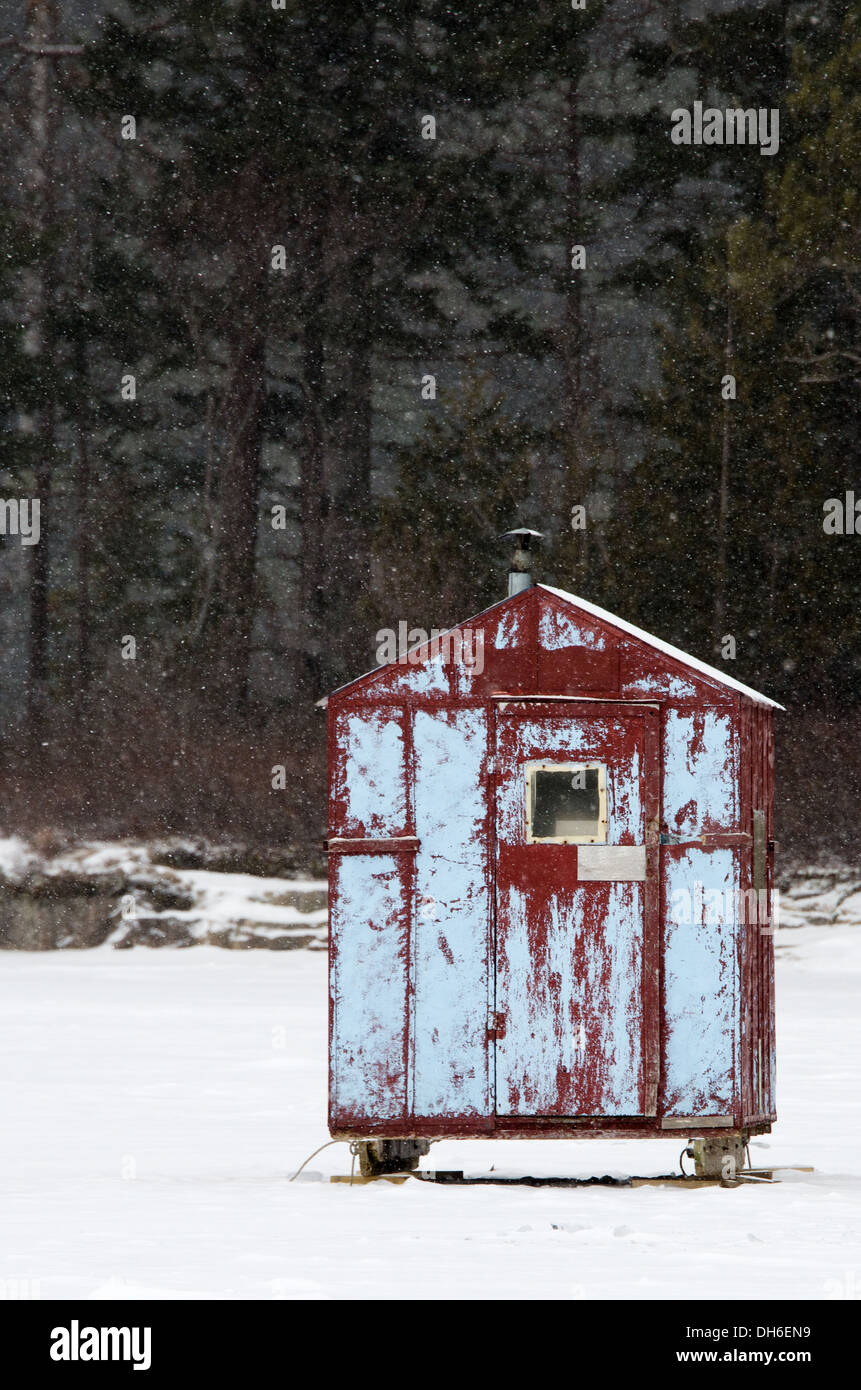 Un rouge et bleu cabane à pêche sur glace dans une tempête de neige. Banque D'Images