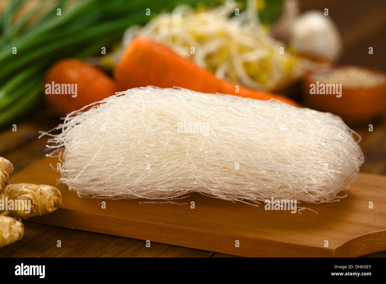 Nouilles de riz cru sur planche de bois avec du gingembre et d'autres légumes (Selective Focus, se concentrer sur l'avant de l'nouilles) Banque D'Images