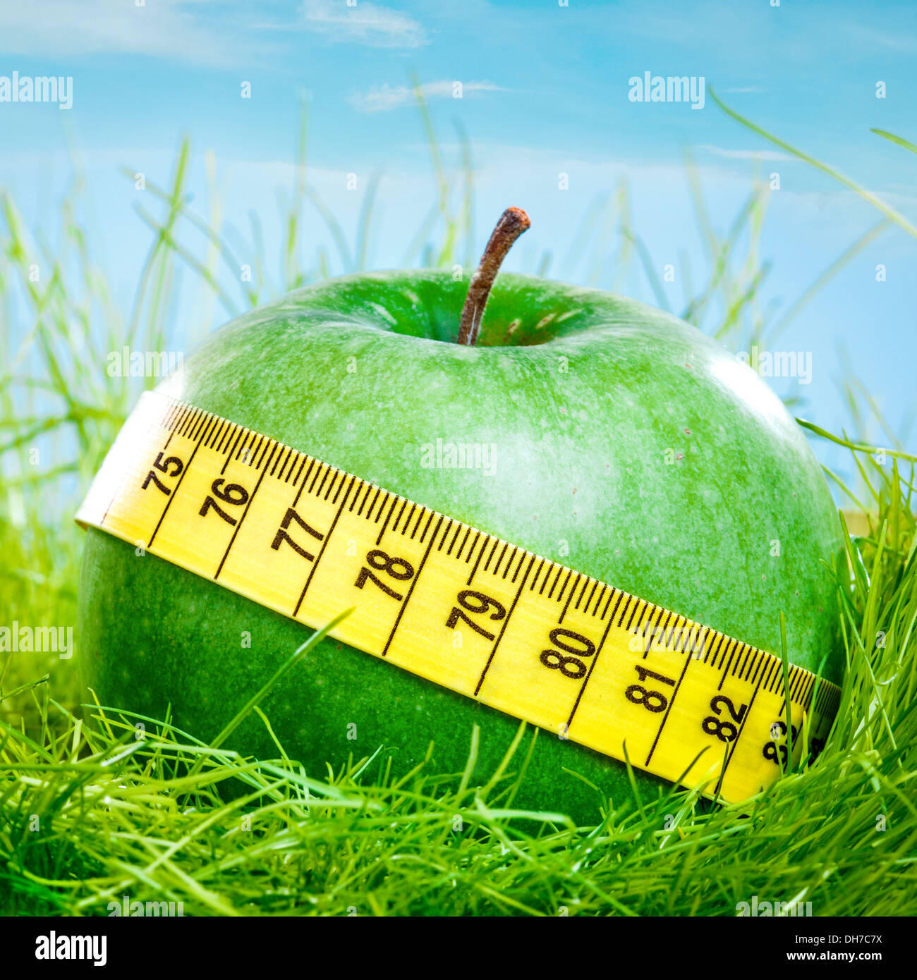 Pomme verte et ruban à mesurer sur l'herbe verte. Banque D'Images