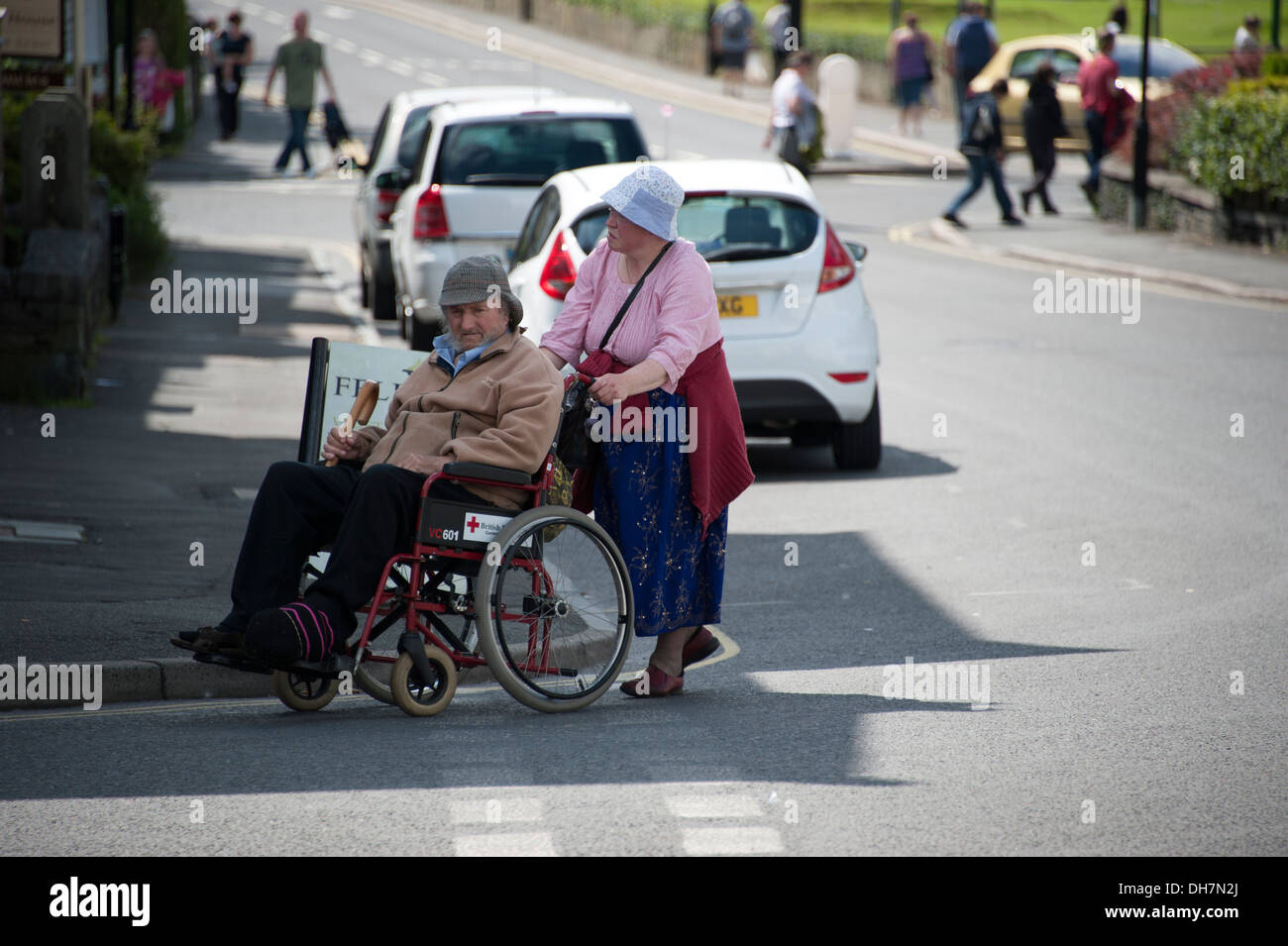 Vieux couple man in wheelchair crossing road Banque D'Images