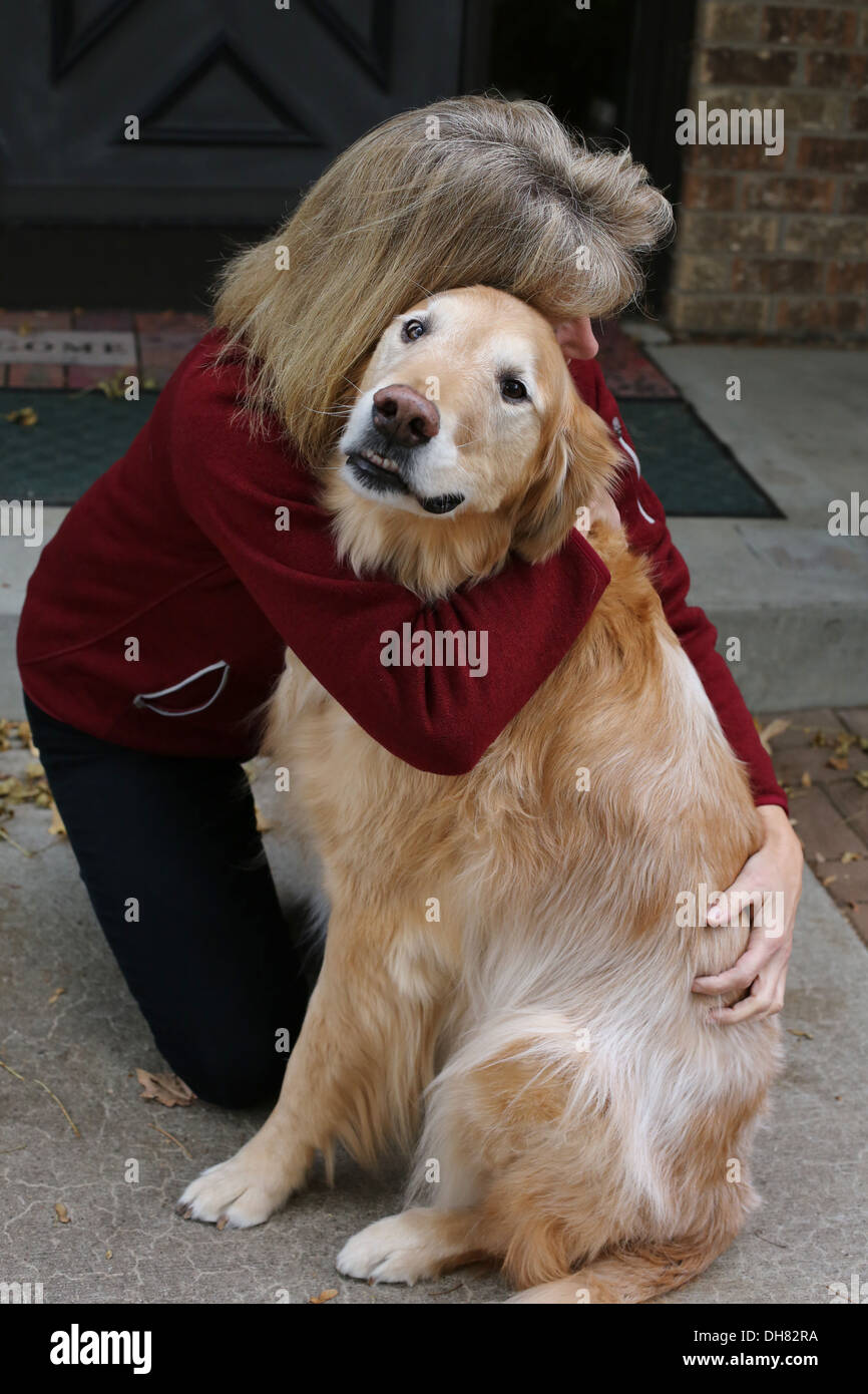 Une femme serrant un vieux chien Golden Retriever. Banque D'Images