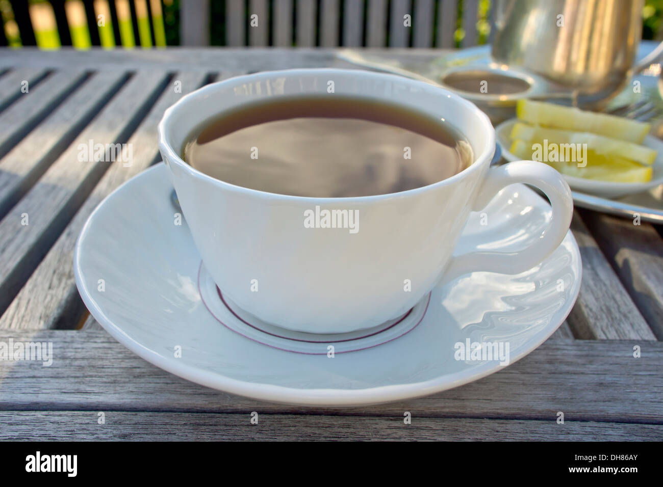 Tasse de thé noir servi sur table en bois dans un jardin. Banque D'Images
