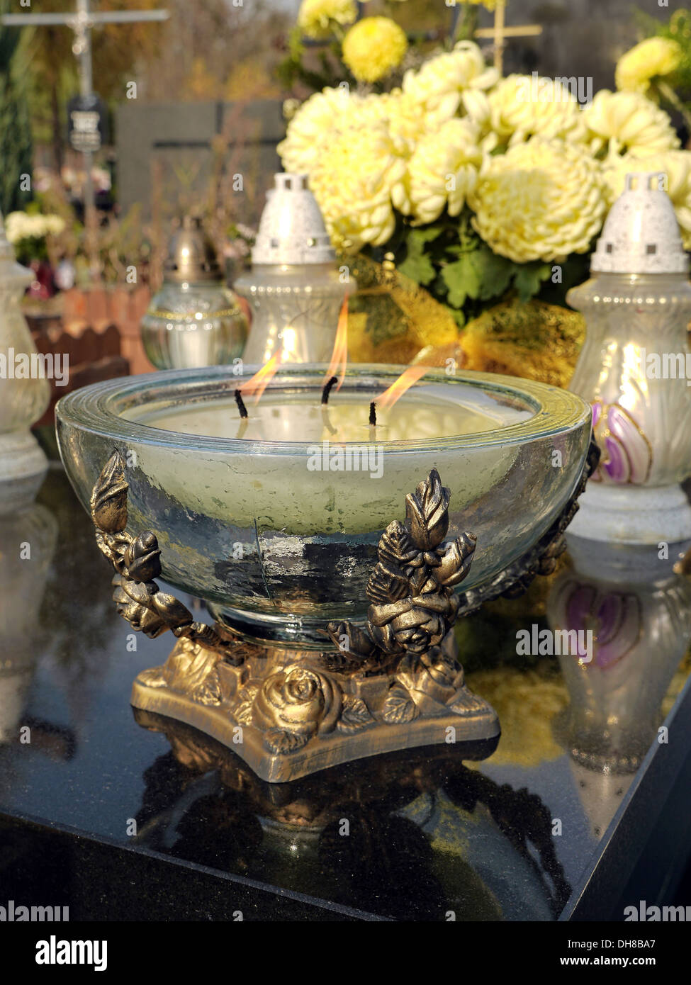 Bougie votive en verre éclairées sur noir en pierre tombale Banque D'Images