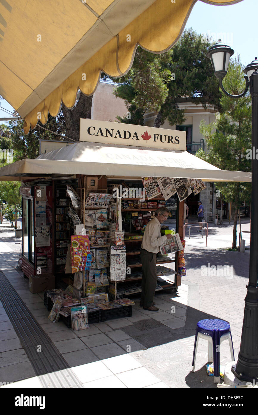 Vieil homme lisant un journal à un kiosque de la rue. La Crète. Banque D'Images