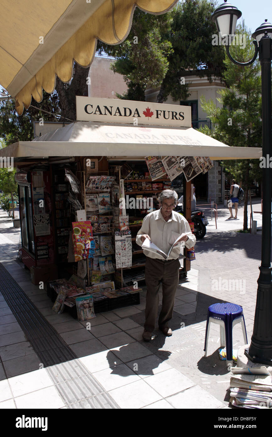 Vieil homme lisant un journal à un kiosque de la rue. La Crète. Banque D'Images