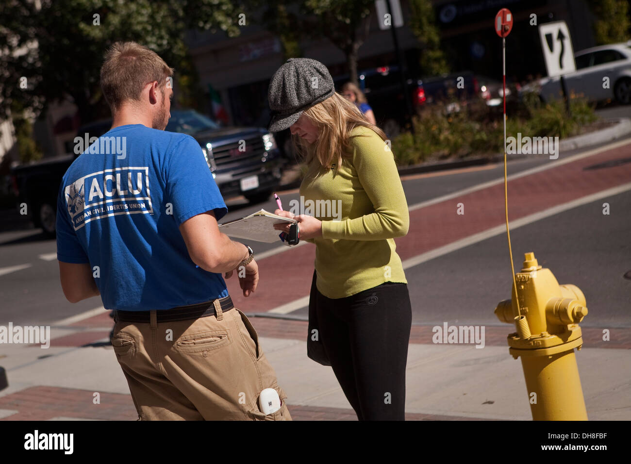 Un homme portant une chemise ACLU pose une femme à signer une pétition dans la ville Banque D'Images