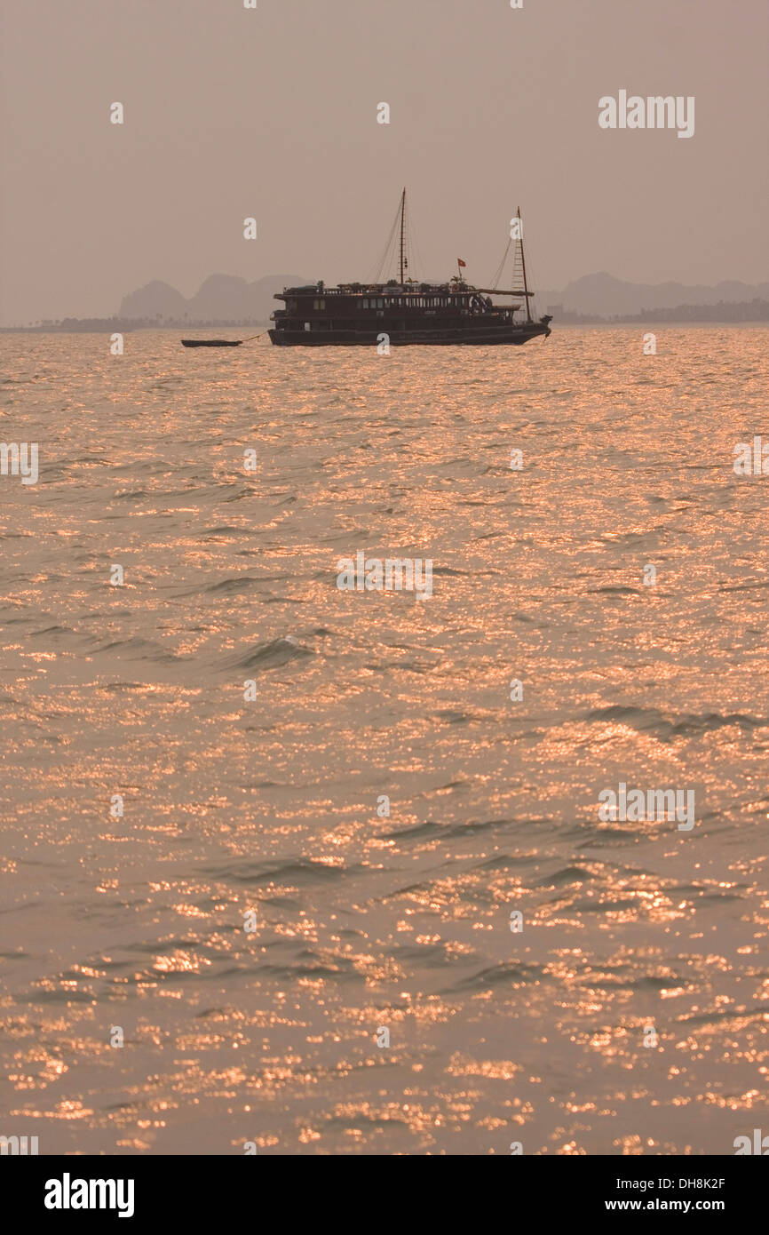 En bois traditionnelles vietnamiennes, les bateaux naviguent dans la baie de Halong au coucher du soleil, le Vietnam. Banque D'Images