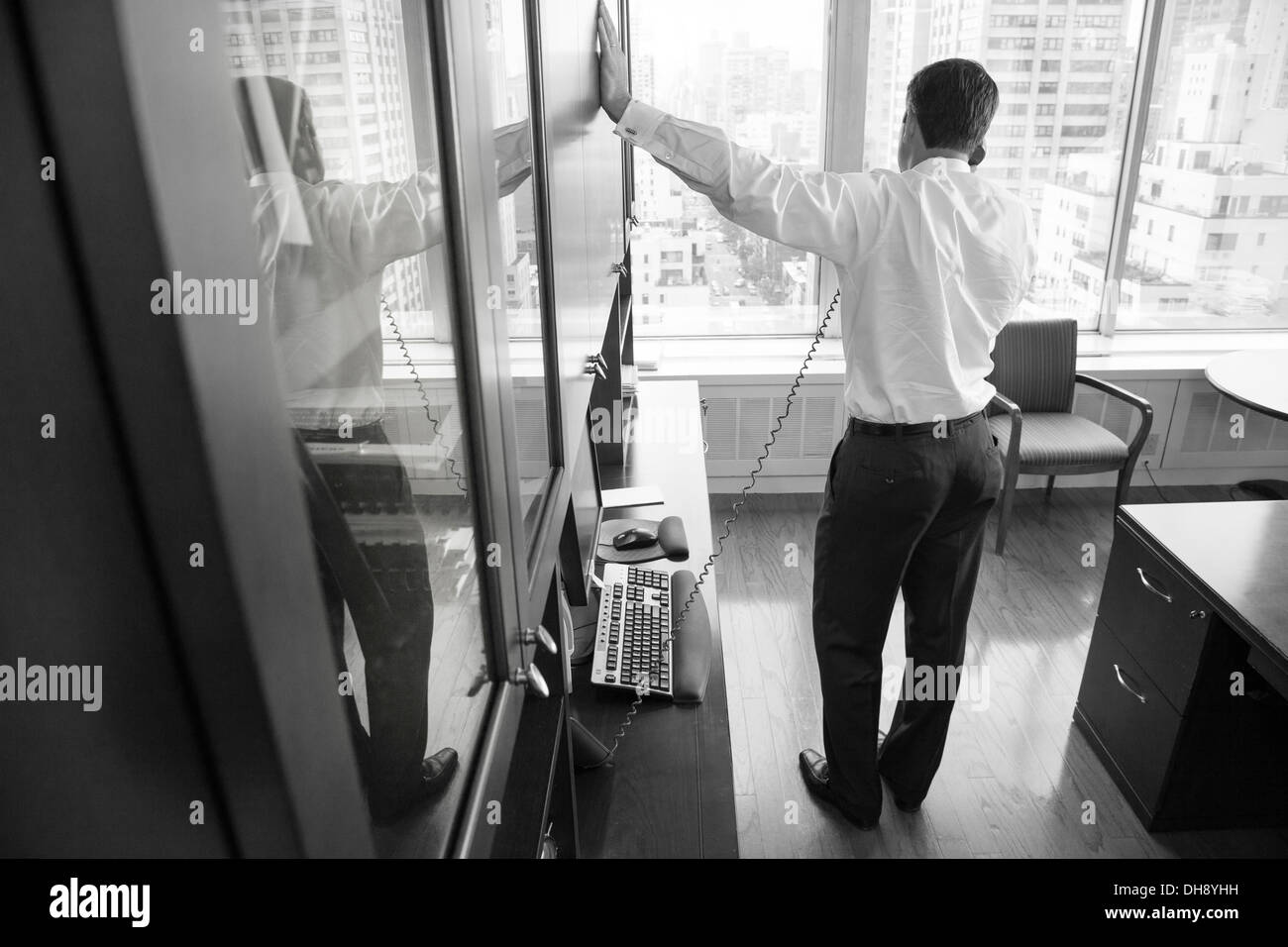 Homme d'affaires sur le téléphone par la fenêtre Banque D'Images