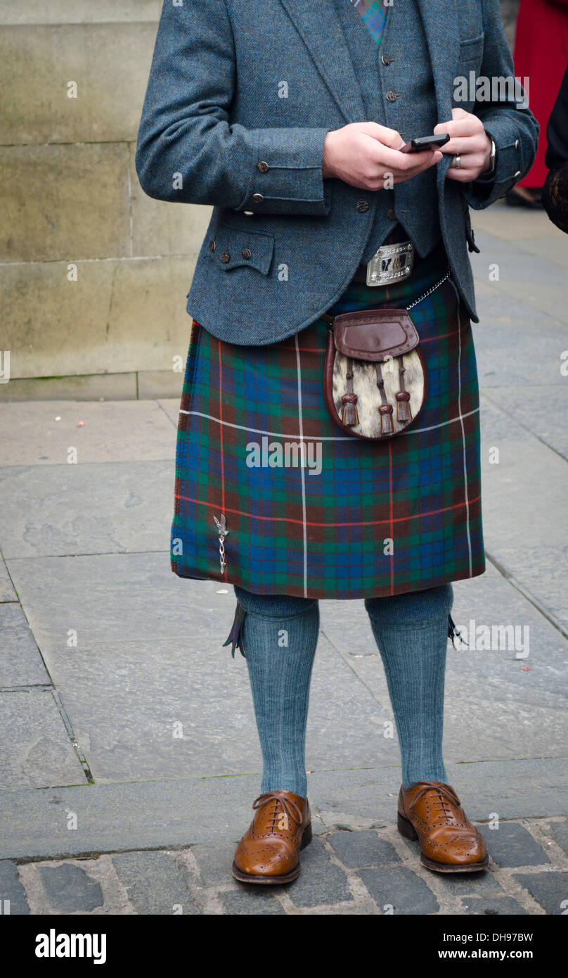 Homme portant un kilt écossais traditionnel et sporran texting on mobile phone Banque D'Images
