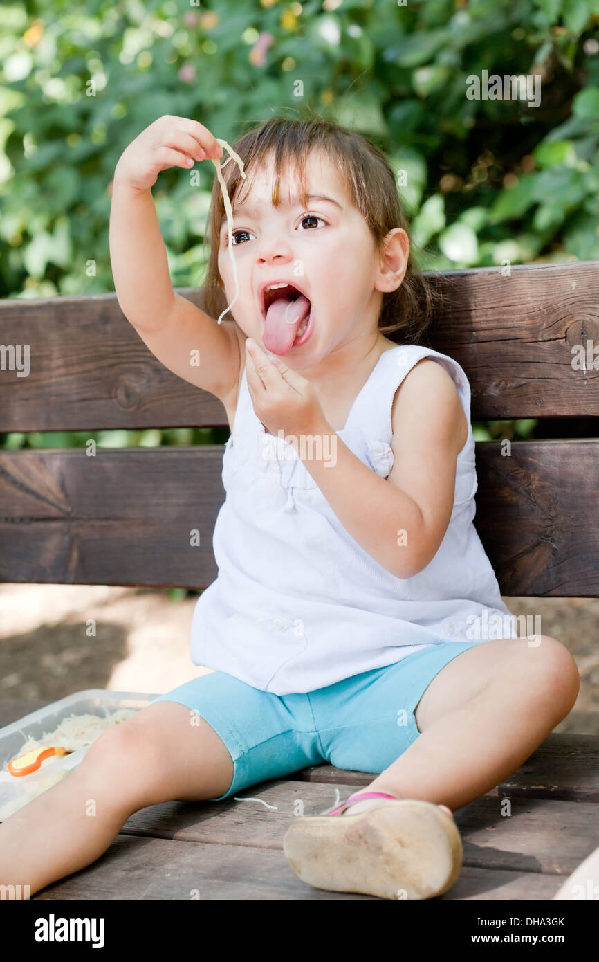 Cute little girl avaler spaghetti avec expression drole Banque D'Images