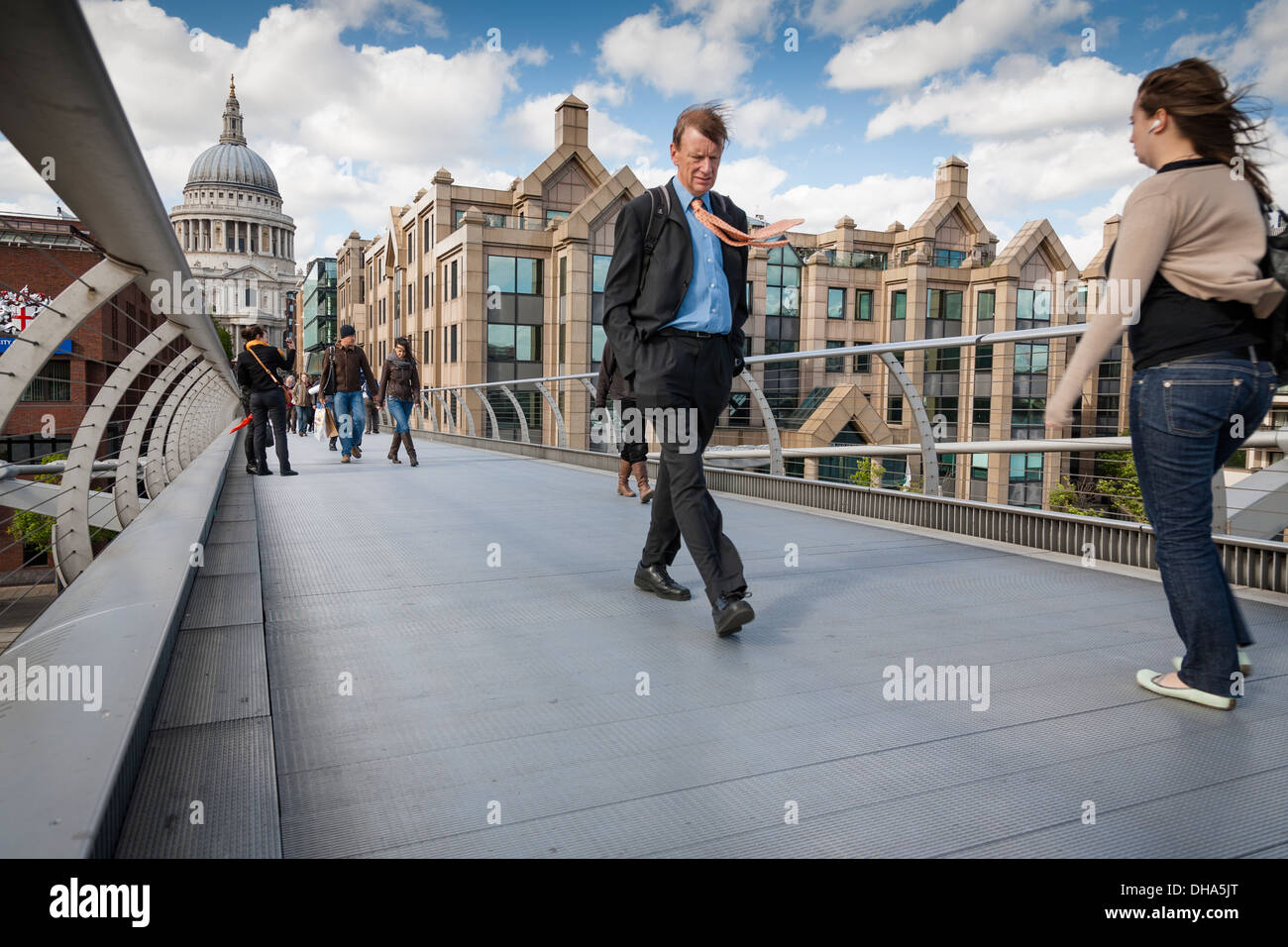 L'homme d'affaires avec des cordelettes qui souffle dans la brise, marche sur la passerelle du millénaire, à Londres, avec la cathédrale St Paul derrière. Banque D'Images
