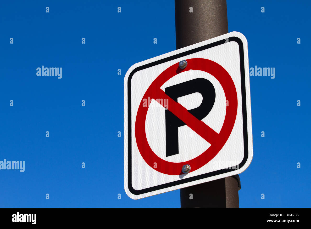 Panneau indiquant un P majuscule avec un cercle rouge indiquant une zone de stationnement n'est attaché à un poteau contre un ciel bleu. Banque D'Images