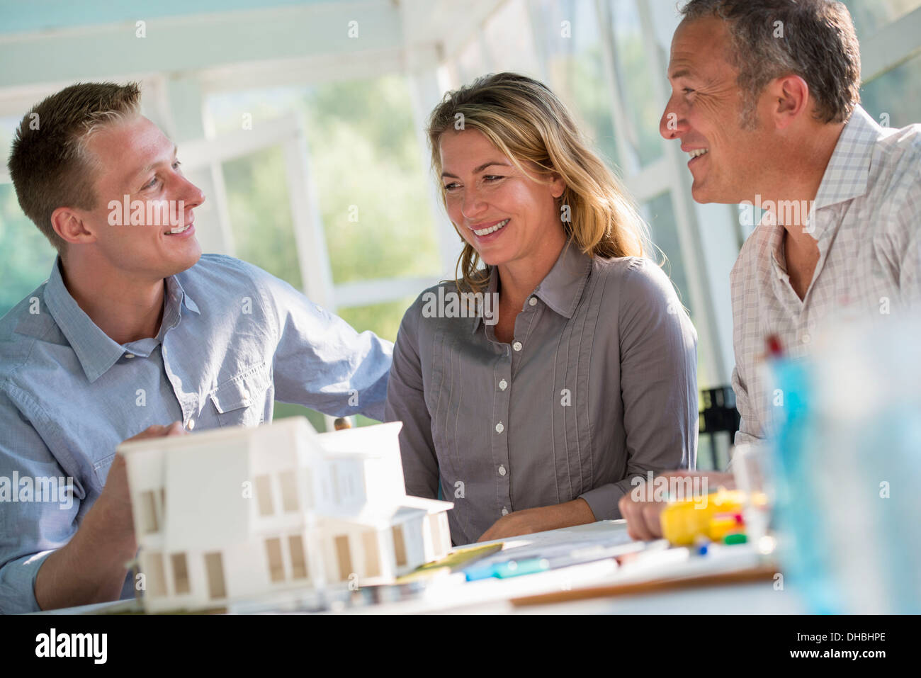 Une cuisine de la ferme. Un modèle d'une maison sur la table. La planification et la conception d'une maison construire. Trois personnes. Banque D'Images