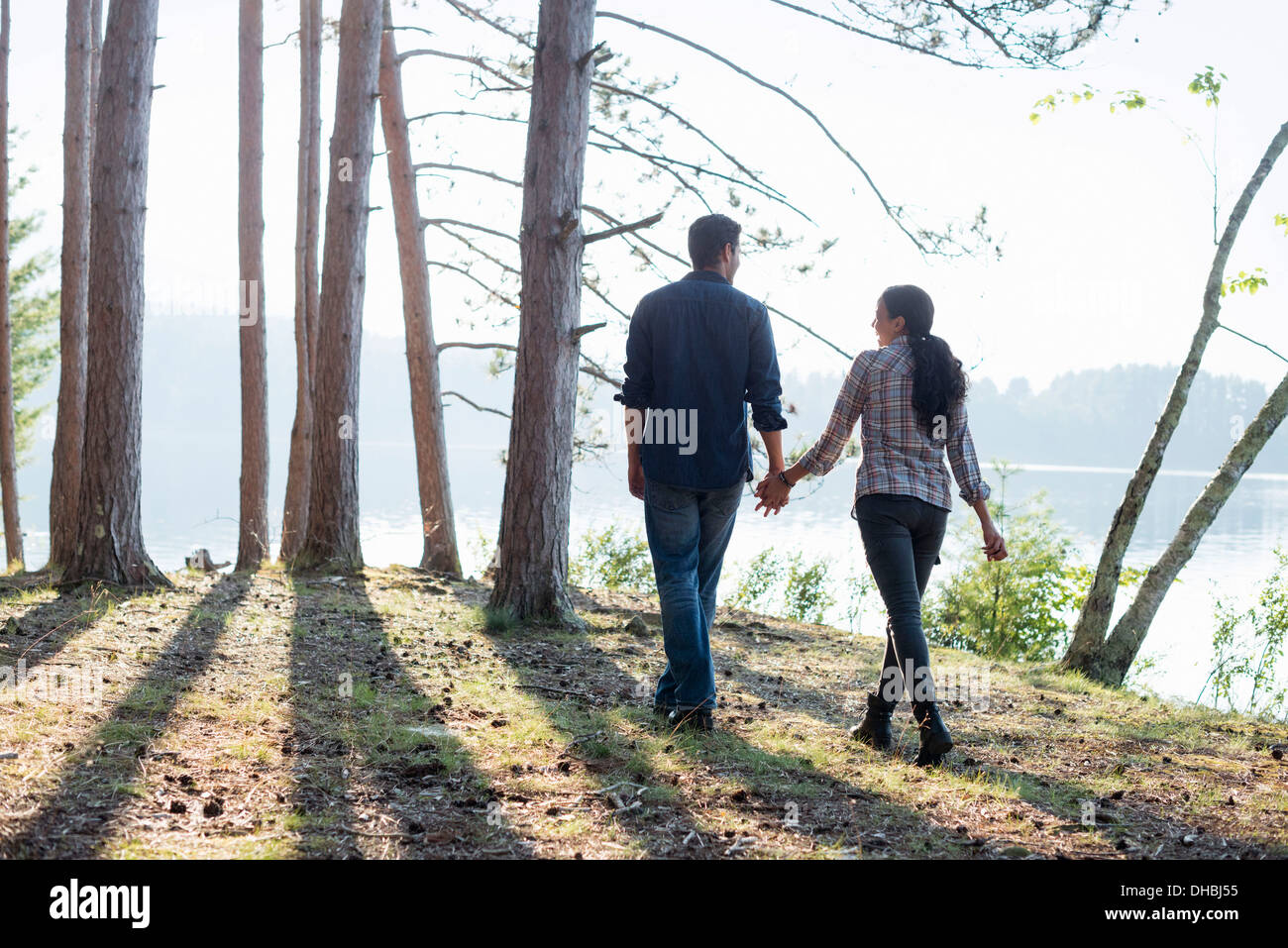 Directement au bord du lac. Un couple en train de marcher dans l'ombre des pins en été. Banque D'Images