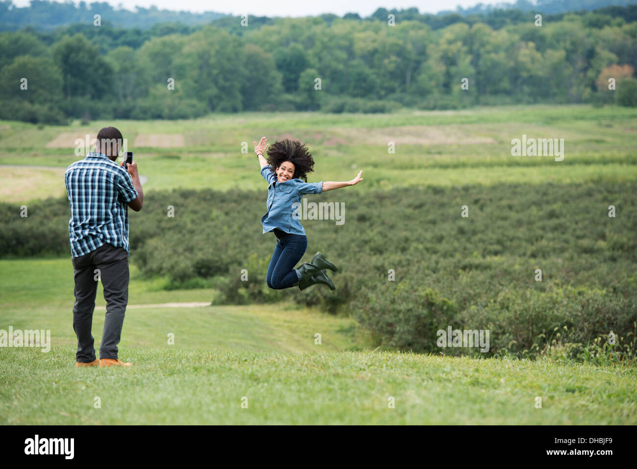 Un homme de prendre une photo d'une femme en sautant en l'air, sautant de joie avec ses bras tendus. Banque D'Images