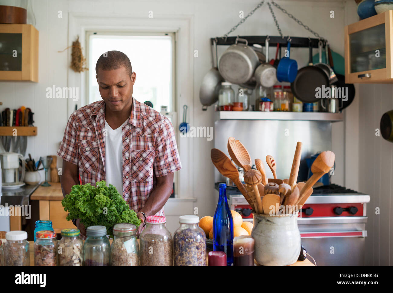 Un jeune homme dans une cuisine la préparation de salades et de légumes. Banque D'Images