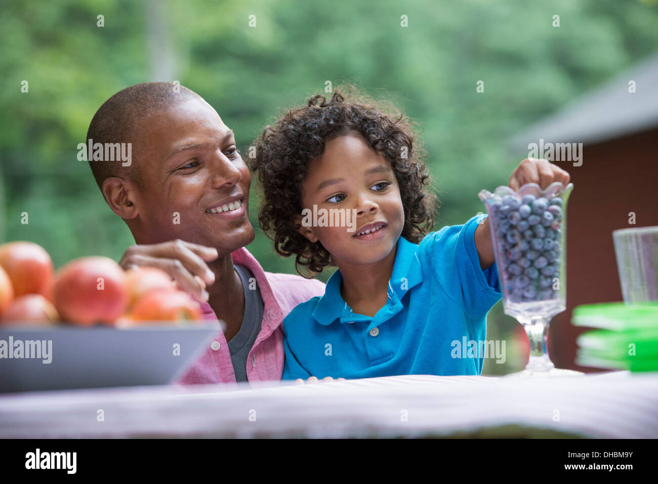 Un pique-nique à la ferme. Les fruits frais sur la table. Un père et son fils, assis côte à côte. Banque D'Images