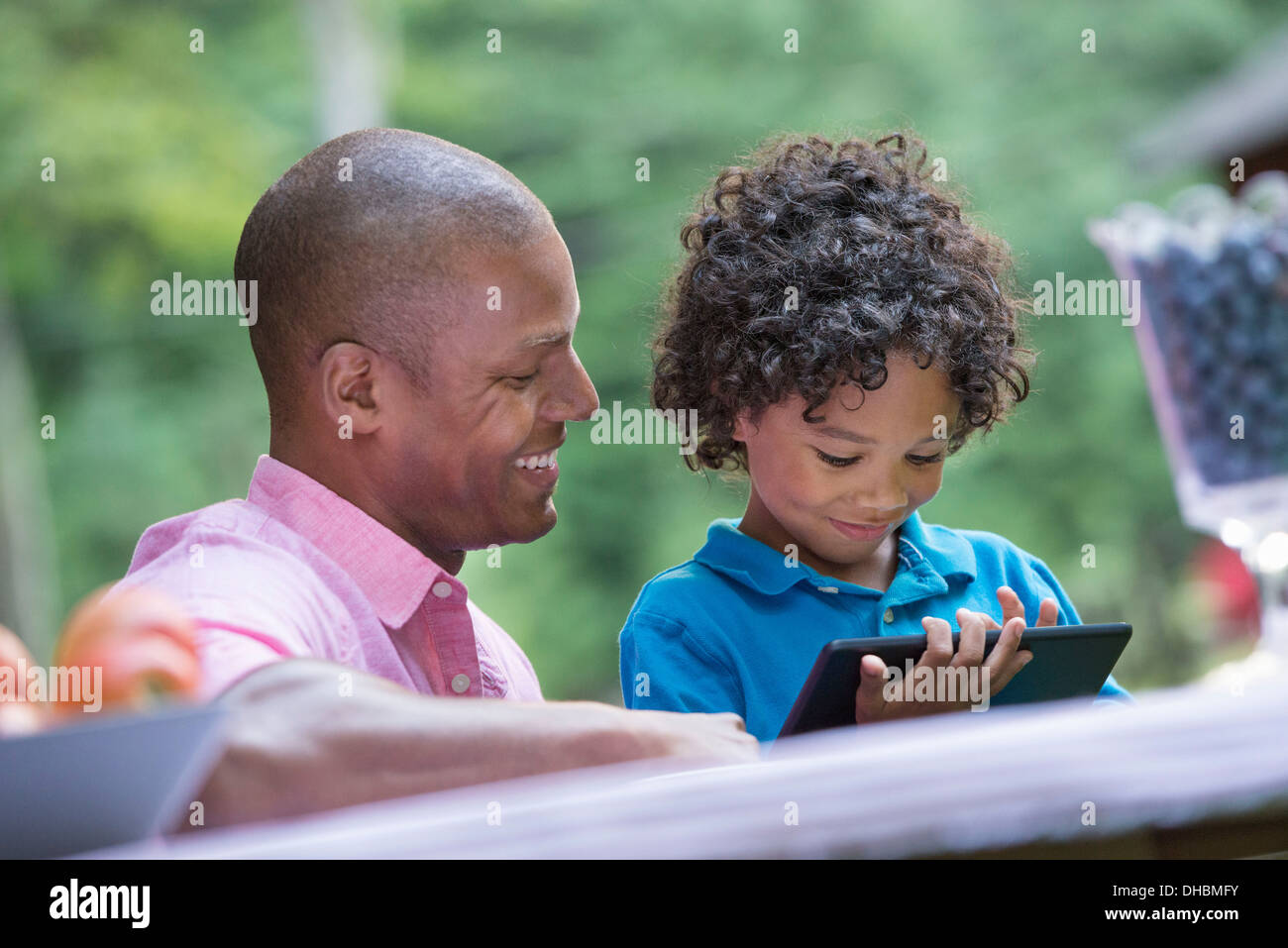 Un pique-nique à la ferme. Les fruits frais sur la table. Un père et son fils, assis côte à côte. Banque D'Images