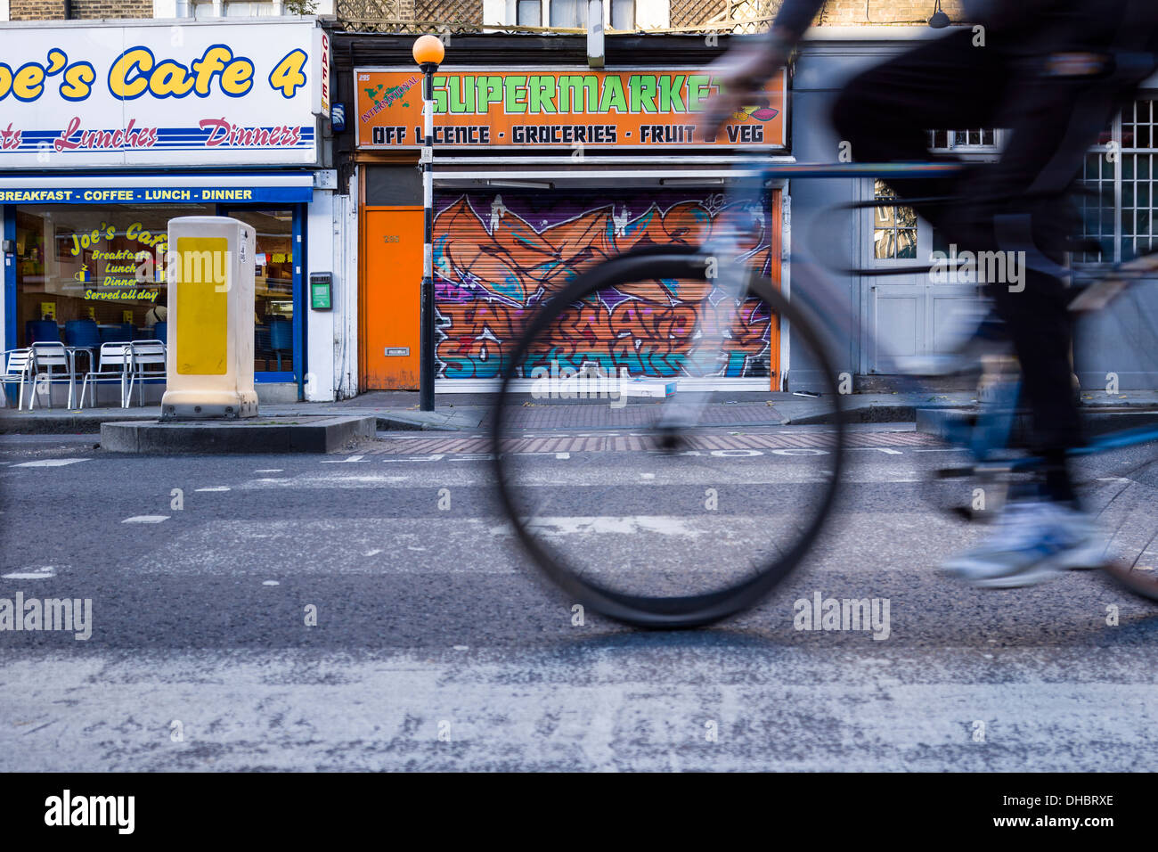 Un cycliste traverse un Pelican Crossing sur la Caledonian Road à Islington au nord de Londres. Banque D'Images