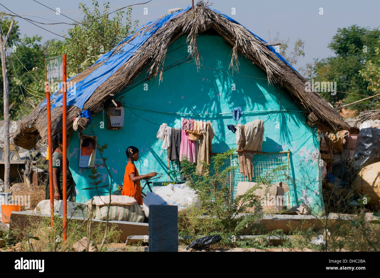 South Indian village hut avec cocotier comme revêtement de toit peint & turquoise lumineux avec jeune fille et de la mère à l'avant Banque D'Images