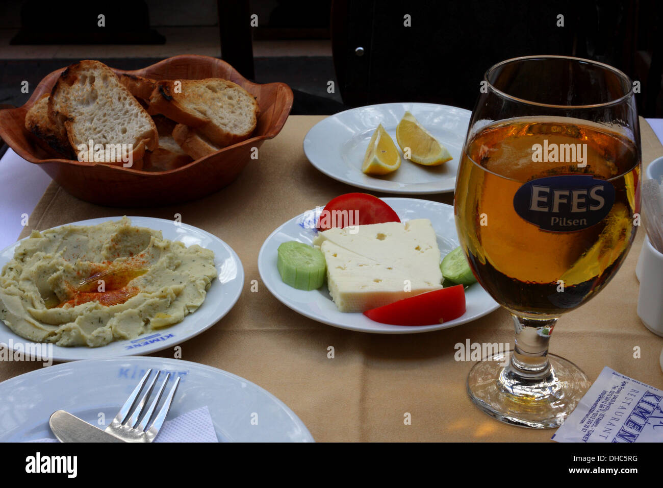 Un repas turc - pain, hoummos, fromage, tomate, concombre, citron et revue de la bière sur une table dans un restaurant à Istanbul Banque D'Images