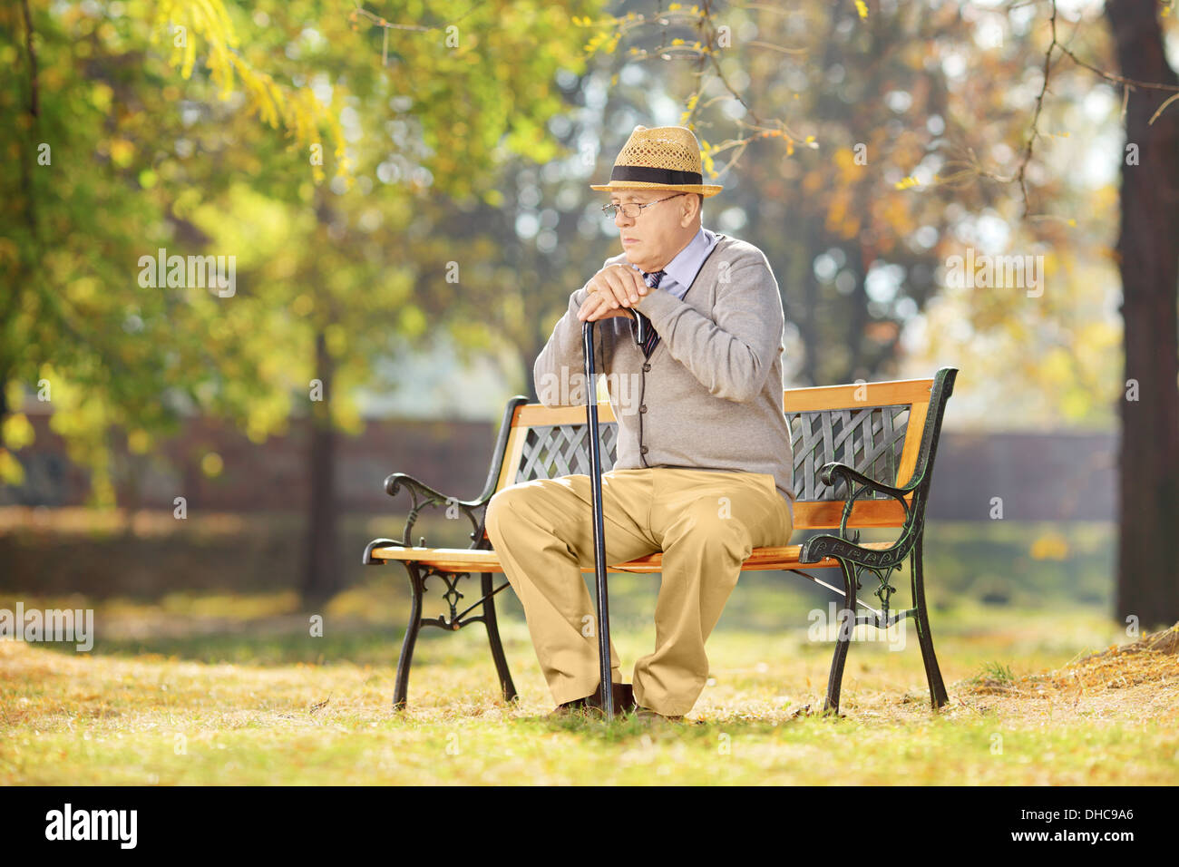 Sad man canne assis sur un banc dans un parc sur une journée ensoleillée Banque D'Images