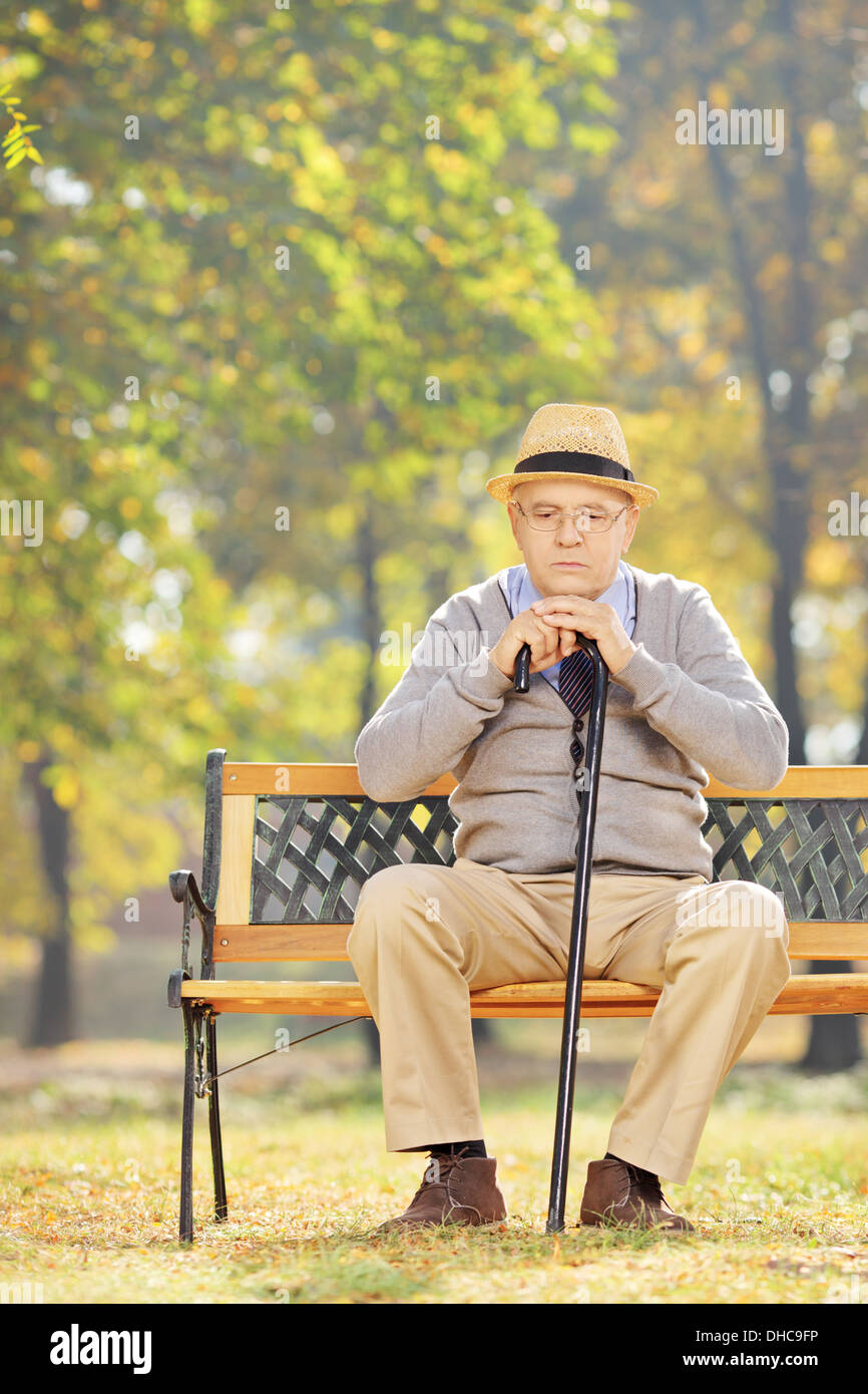 Happy man avec une canne assis sur un banc en bois dans un parc Banque D'Images