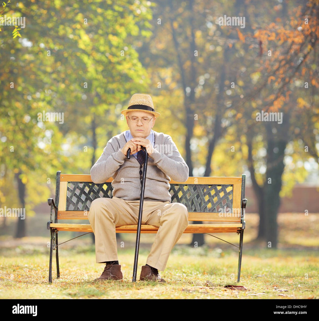 Happy man avec une canne assis sur banc en bois dans un parc sur une journée ensoleillée Banque D'Images