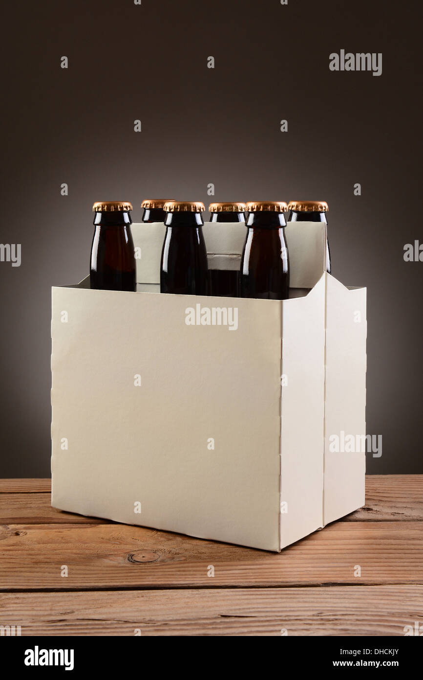 Libre d'un six-pack de bière brune bouteilles sur une table en bois rustique. Format vertical avec un léger gris foncé à l'arrière-plan place. Banque D'Images