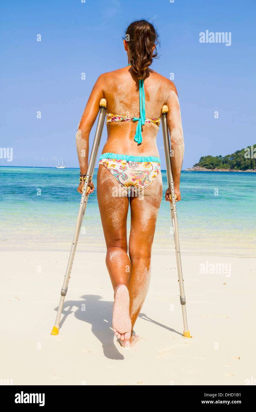 La Thaïlande, l'île de Koh Surin, femme avec des béquilles debout à la plage de sable blanc Banque D'Images