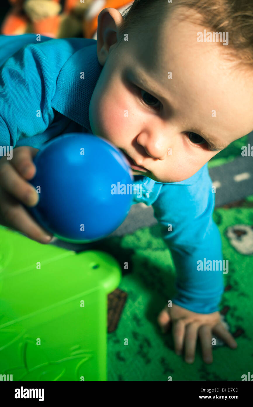 Baby boy playing with ball à l'intérieur. Banque D'Images