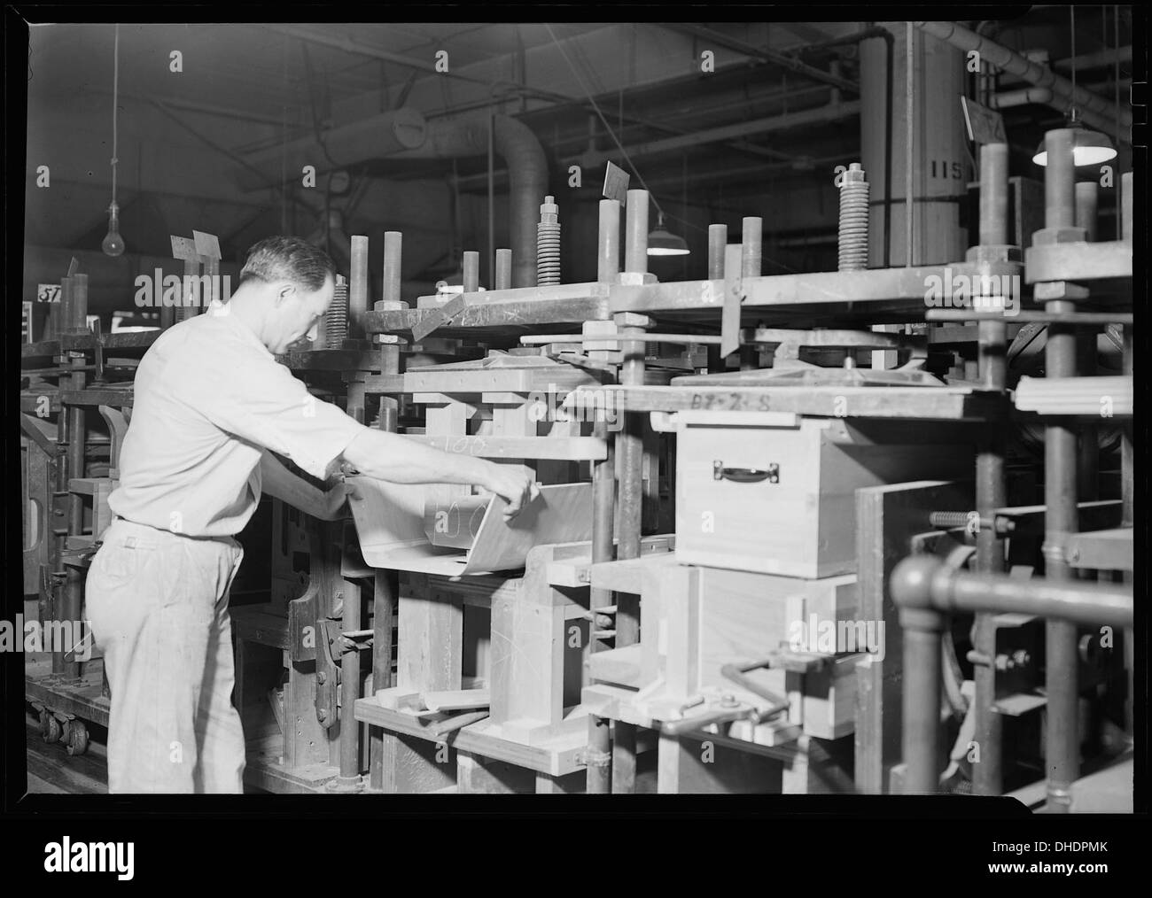 À l'usine RCA Victor à Camden, New Jersey, un assembleur d'armoires travaille à la construction de la taille d'une armoire, qui fait partie du processus de fabrication des produits RCA. Banque D'Images